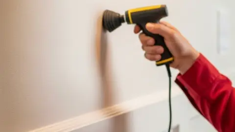 Leak detection probe held against a wall